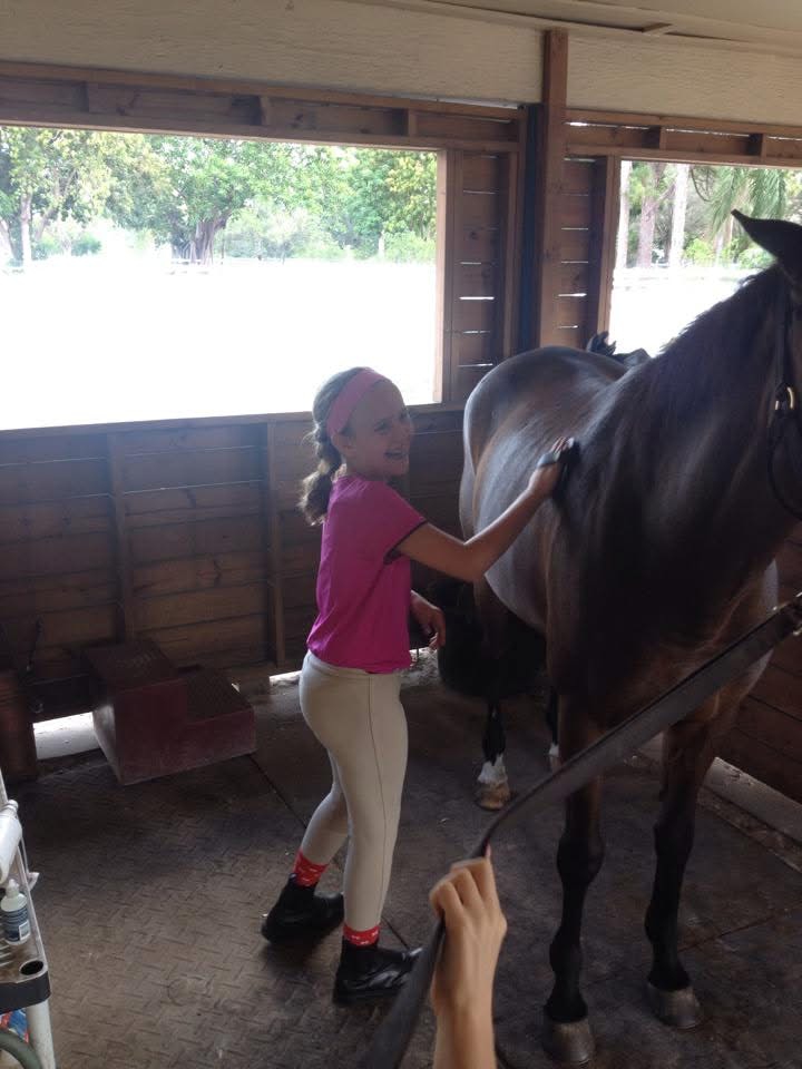 Hannah Leon brushing a horse as a young girl