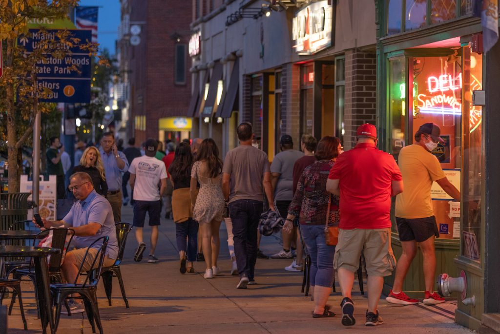 A large group of people walking uptown on the sidewalk 