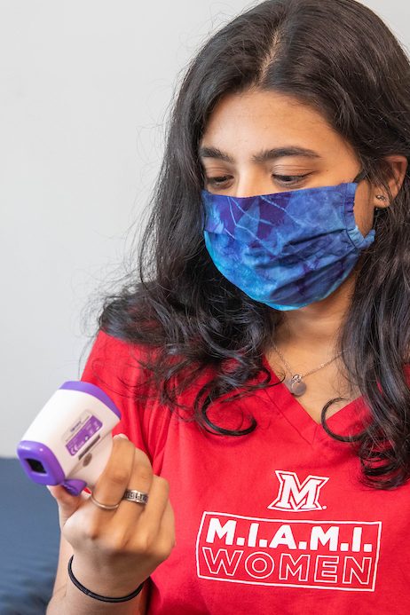 Miami student in a residence hall looking at a thermometer