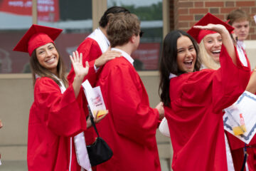 Graduates in caps and gowns walking into commencement.