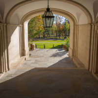 Looking through the Upham Arch with beautiful green grass and colorful fall trees in the distance.