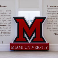 A big red capital letter M figure sitting between white walls containing Miami University's Code of Love and Honor