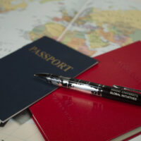 A notebook, pen, and passport lying on a world map
